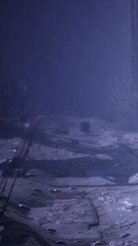 A person moves through a dimly lit space filled with debris and shadows. The area shows signs of wear and neglect. Light cuts through the darkness revealing details of the environment.