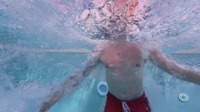 Underwater slow motion shot of man jumping into swimming pool. Original shot at 100fps, now 25fps