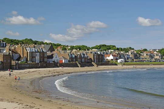 Houses along a beach with walkers by the sea under a blue sky on a sunny day, North Berwick, Scotland, United Kingdom