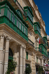 Fototapeta premium Traditional green wooden balconies on the historic limestone facade in Valletta Malta 