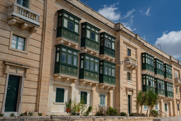Fototapeta premium Traditional green wooden balconies on the historic limestone facade in Valletta Malta 