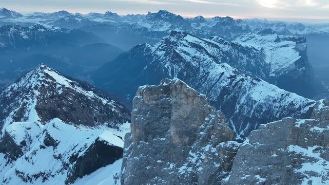 Aerial view of the snow-covered peaks of Parco Naturale Paneveggio Pale di San Martino under a soft blue sky in Primiero San Martino di Castrozza, Trentino-Alto Adige, Italy.