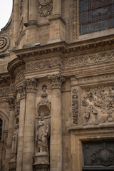 Fototapeta premium Vertical view of ancient baroque cathedral facade. Detailed stone carvings, columns and holy statues. Abstract historic european architecture background. High resolution 33MP. 