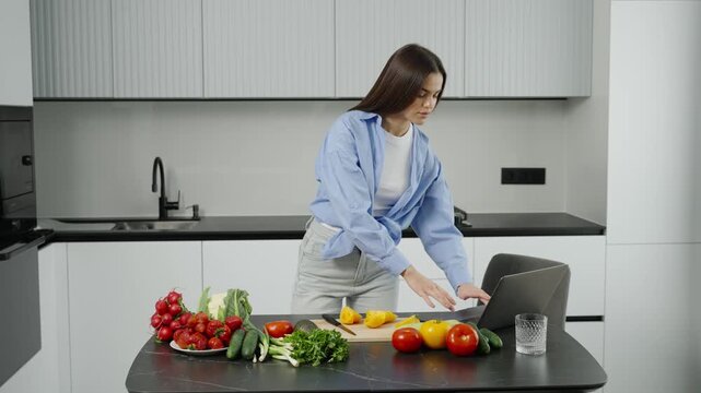 Young woman following online recipe while cooking