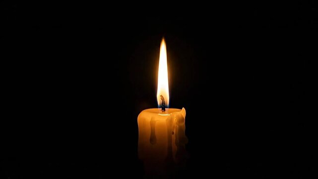 A single burning candle glows brightly against a dark and solid black background