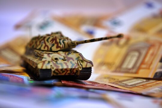 Toy tank on euro banknotes symbolizing military spending and defense budget in Europe