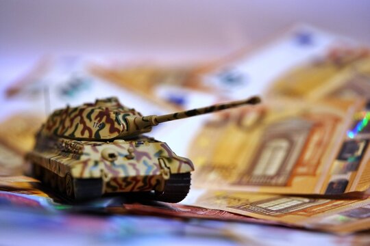 Toy tank on euro banknotes symbolizing military spending and defense budget in Europe