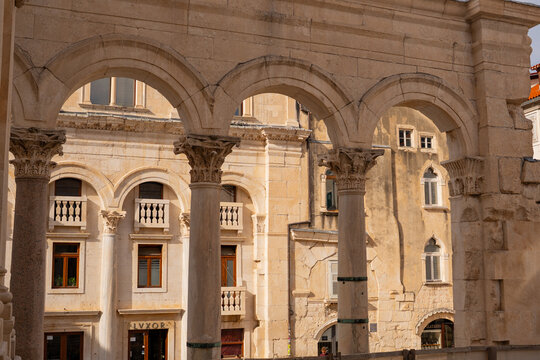 Epic Split Diocletian palace peristyle panorama. 
Cinematic ground view of ancient Roman limestone 
colonnade arches and historic venetian buildings 
in old town Split, Croatia.

