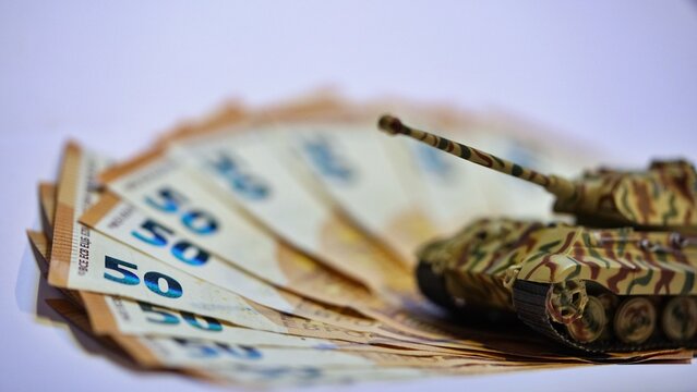 Toy tank on euro banknotes symbolizing military spending and defense budget in Europe