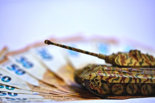 Toy tank on euro banknotes symbolizing military spending and defense budget in Europe
