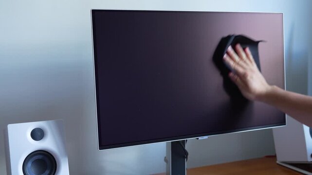 A person cleaning a computer screen with a cloth