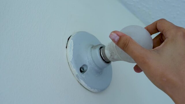 Woman screwing a light bulb into the ceiling fixture