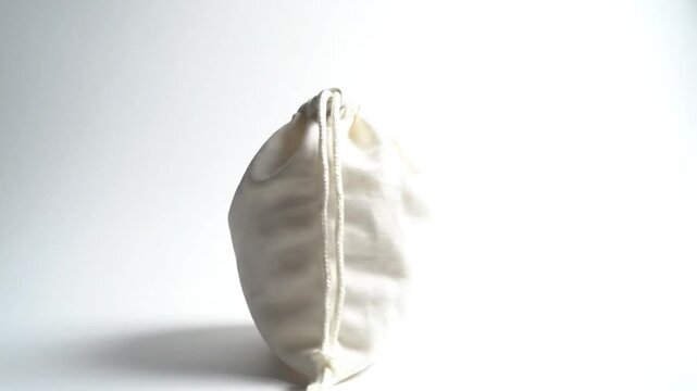 Rotating close up of a small white drawstring bag on a clean white background