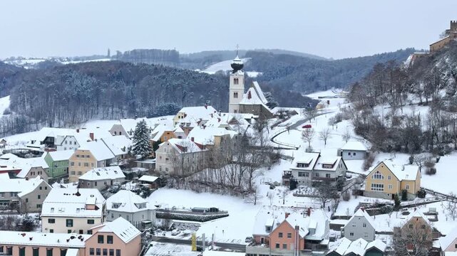 Aerial view of the snow-covered village of Riegersburg with its parish church and historic houses nestled among winter hills in Riegersburg, Styria, Austria.