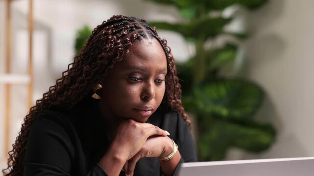 African woman working remotely, focusing on her laptop at home