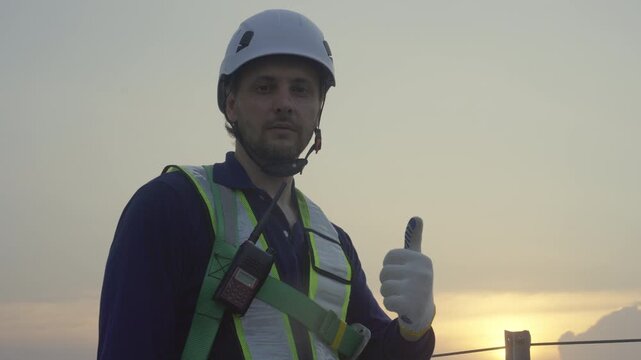 Engineers maintenance solar panels rooftop green energy safety inspection technician at sunset and sunrise, focused worker adjusts helmet, harness, vest during repair on high roof, thumbs up