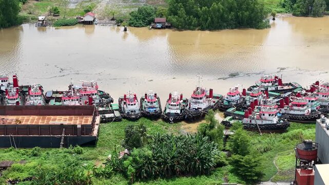 Aerial view of tugboats parked in a row on the riverbank next to barges