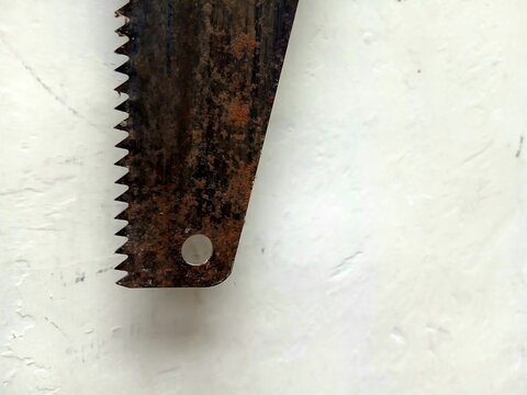 Close up shot of an old rusty hand saw blade with sharp teeth and hanging hole on a plain background