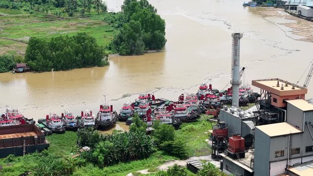 Aerial view of tugboats parked in a row on the riverbank next to barges