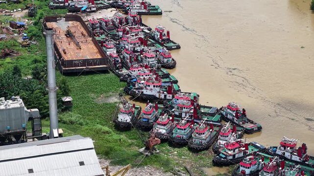 Aerial view of tugboats parked in a row on the riverbank next to barges