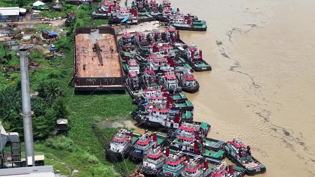 Aerial view of tugboats parked in a row on the riverbank next to barges