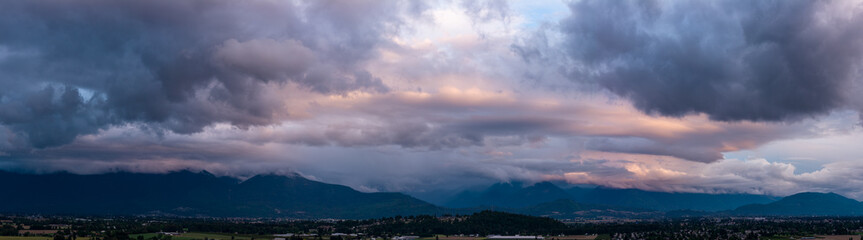 Obraz premium Dramatic Storm Clouds Over Chilliwack Mountains at Sunset Panorama in British Columbia, Canada