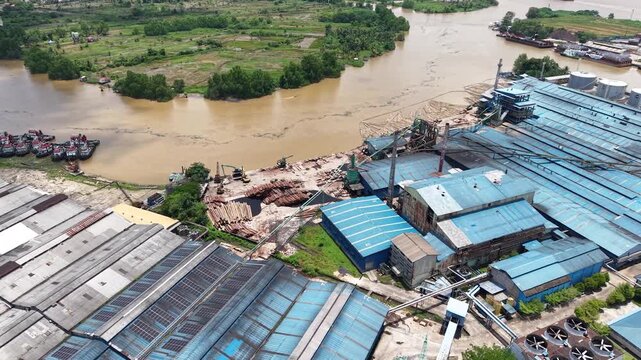 Aerial view of a plywood factory with stacks of logs in front of it as raw material for plywood production