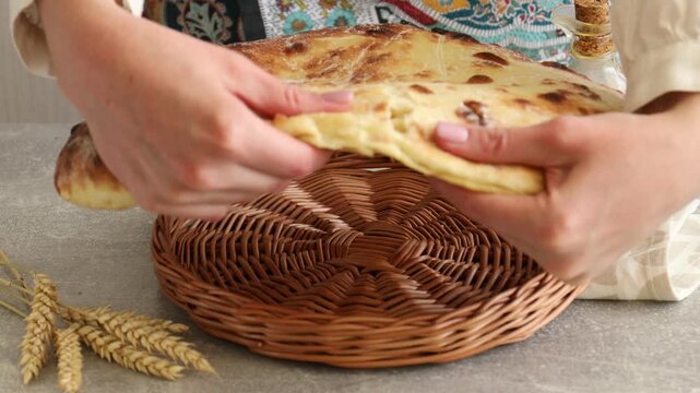 Woman breaking tasty flatbread at light grey table, closeup