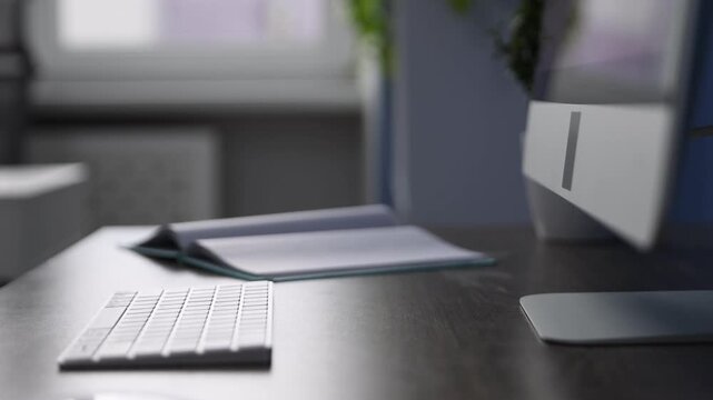 Computer and notebook on wooden desk in office, closeup. Camera moving in