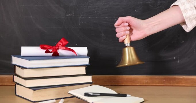 School holidays. Teacher ringing golden bell, books, stationery and diploma near chalkboard, closeup