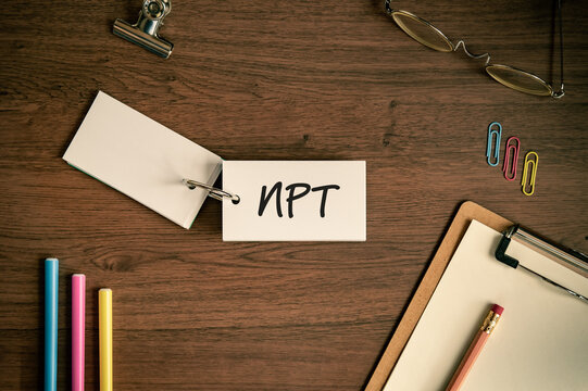 Eye-catching image of NPT text on word card. The word stands for Non-Proliferation Treaty. Shown with pens, clips, clipboard.