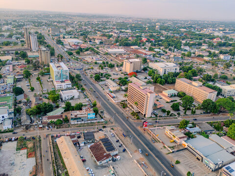 Aerial view of Ahmadu Bello Way with urban buildings, lush green trees, and city traffic under a clear sky in Kaduna, Kaduna, Nigeria.