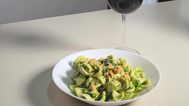 piatto di orecchiette alle cime di rape con un calice di vino rosso