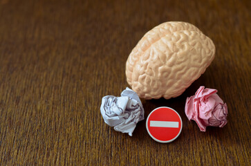 Fototapeta premium Behavioral correction and mental self-restraint concept showing a brain model with a tiny traffic stop sign and crumpled paper balls