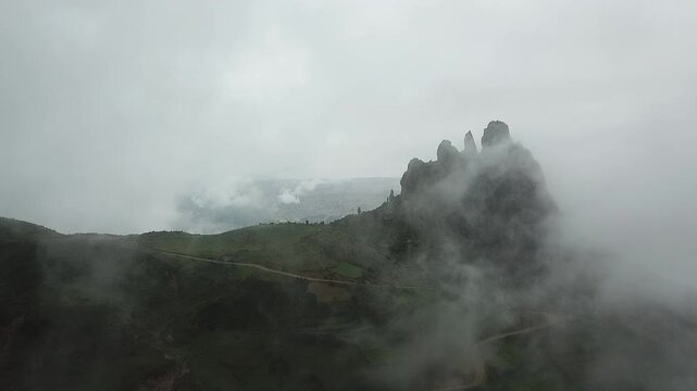 An aerial view emerging from the clouds amidst partial rain reveals a mountain called Muela del Diablo (Devil's Tooth).