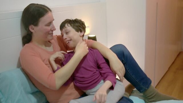 A middle-aged mother strokes the head of her daughter with cerebral palsy and hugs her. A tender family moment between parent and child. Lifestyle of family with a child with special health needs.