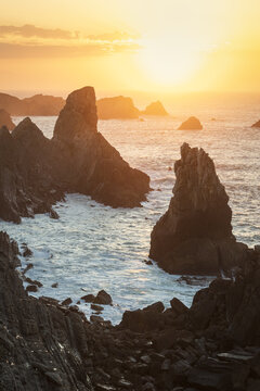 View of the dramatic rock formations and sea stacks at sunset along the rugged coastline of Liencres, Cantabria, Spain.