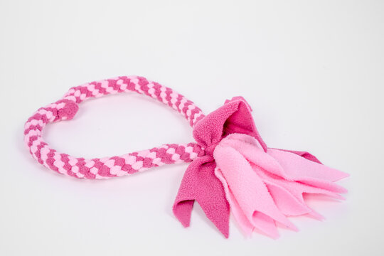 Pink braided rope dog chew toy with knotted fringe end on clean white background, pet dental hygiene product, minimal commercial concept.