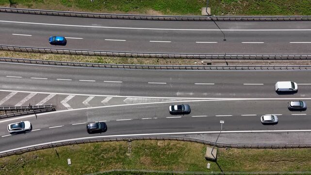 Highway Flow: Aerial view of cars and vans navigating a multi-lane highway interchange, showcasing the dynamic movement of traffic under a bright, clear sky.