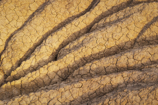 View of the cracked and eroded clay formations of Bardenas Reales with deep shadows and dry textures in Navarre, Spain.