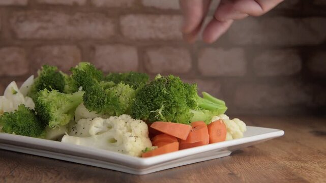 Platon blanco con vegetales cocidos, sobre una mesa de madera y pared rustica de ladrillos
