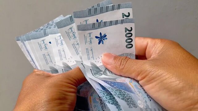 Counting 2000 rupiah as a means of payment in Indonesian. Concept of economy, debts, purchases, trade and payment.