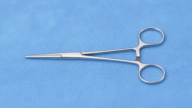 A stainless steel hemostat on a blue surgical drape.