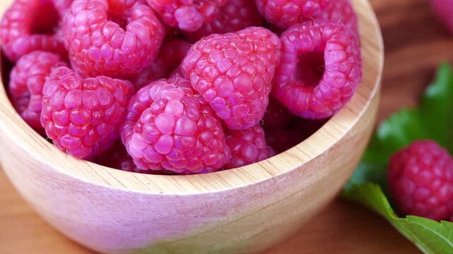 Fresh red raspberries in a basket on a rustic wooden background, Ripe organic raspberries in a wicker basket on wood. Premium berries for gourmet dessert concepts