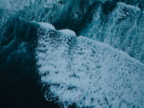 Aerial view of crashing waves with white foam and deep blue water at La Jolla Cove San Diego, California, United States.