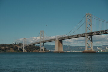 Obraz premium The iconic San Francisco-Oakland Bay Bridge (I-80) , a 8.4-mile, double-decked, state-owned toll bridge connecting San Francisco and Oakland via Yerba Buena Island with blue skies