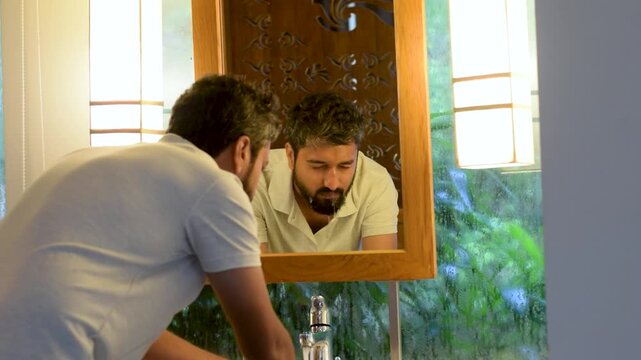 Indian man washing his face early morning as part of daily routine, showing hygiene, skincare, freshness, self care and wellness in a calm home setting before starting a productive day ahead calmly.
