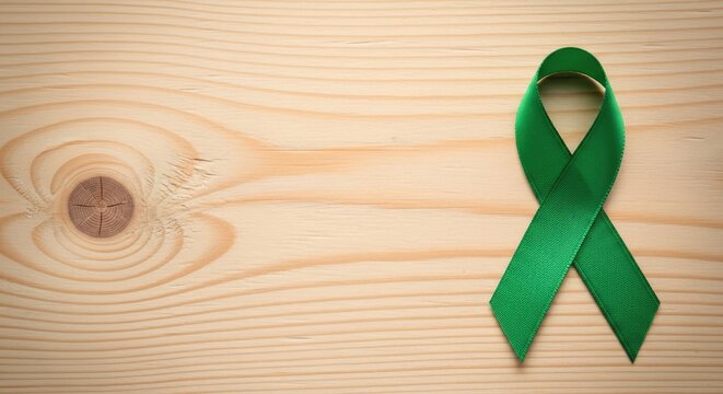 Green ribbon on light wooden surface with visible grain and knothole grain pattern