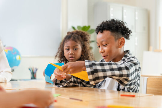 Diverse students making paper planes in a classroom, Happy children enjoying creative paper craft activity at school, Students learning and playing with colored paper in classroom