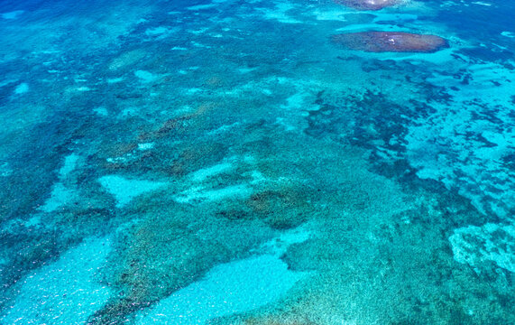 Aerial view of the vibrant coral reefs and crystal clear turquoise waters surrounding the island Guanaja, Bay Islands Department, Honduras.